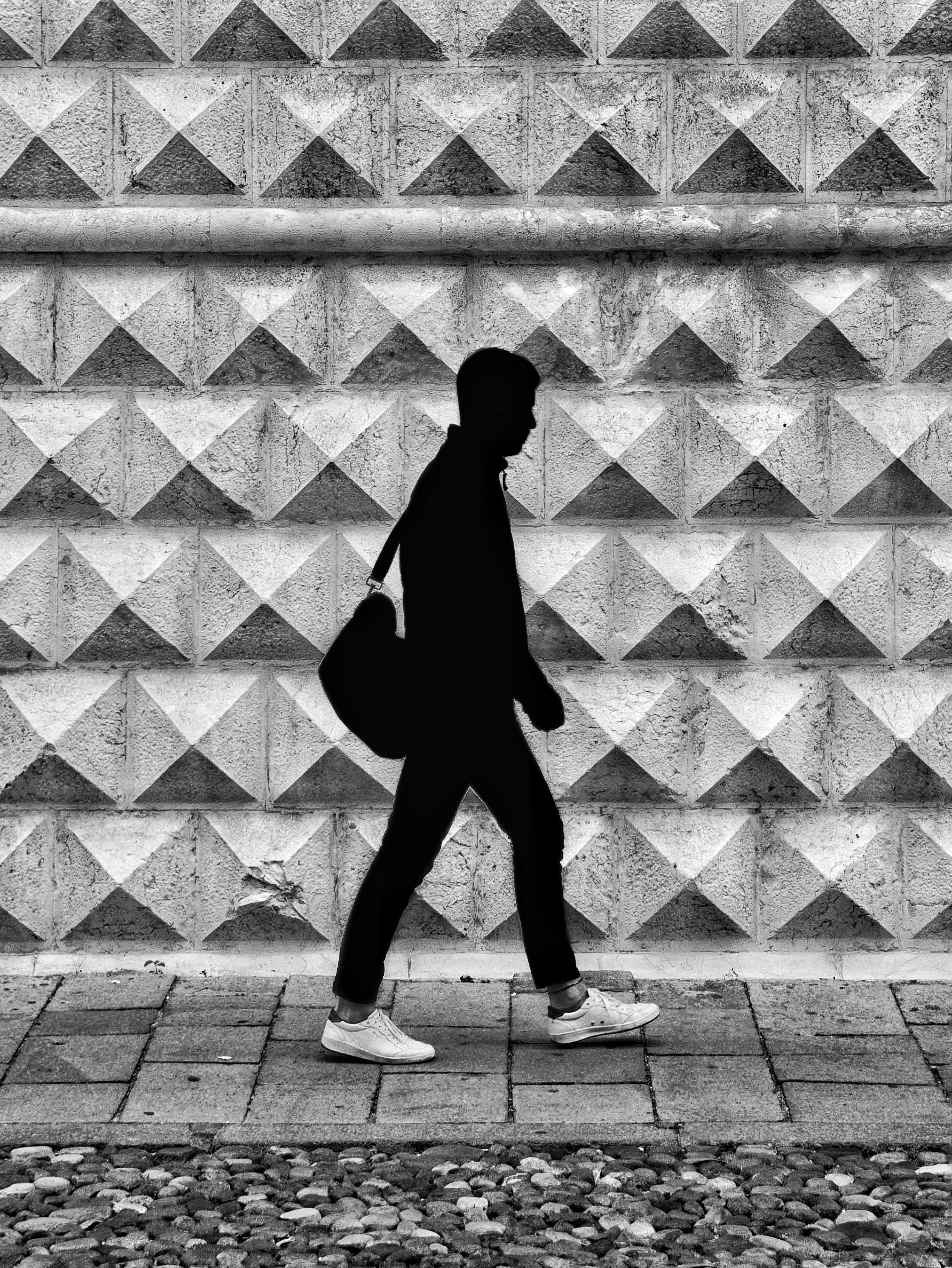 man walking in front of textured wall